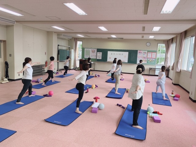 女性が10人程度教室に集まりヨガをしている様子の写真