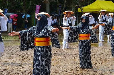 黒い頰被りをして踊る女性たちの写真