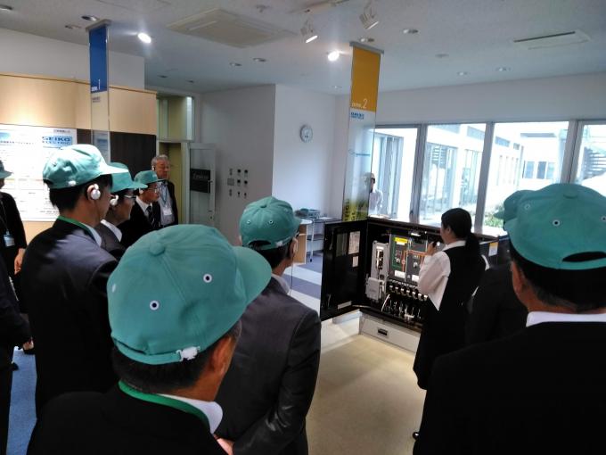 機械の説明を聞く参加者たちを後ろから見た写真