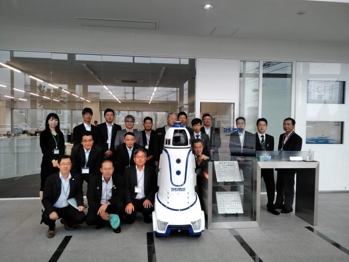 自動監視ロボットと並んで記念撮影をする参加者たちの写真