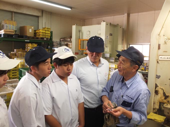 工場で作業員の話を聞く生徒たちの写真