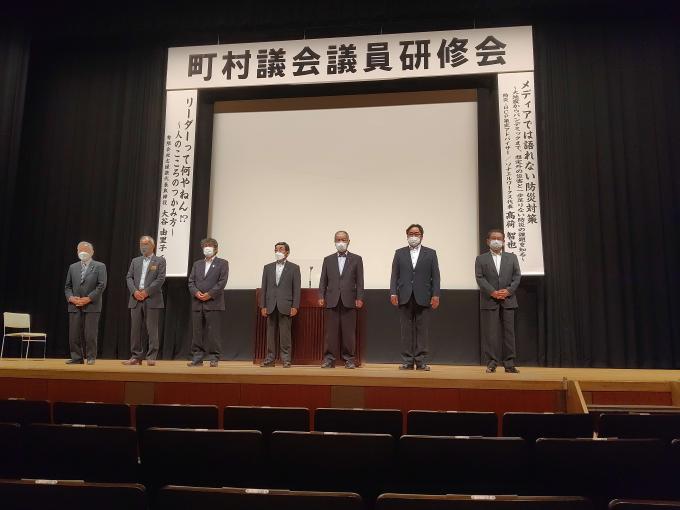 鹿児島市の町村議会議員研修会にて、壇上に男性7人が立っている写真