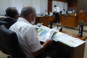 資料を見ながら座って話を聞いている議員を後ろから見た写真