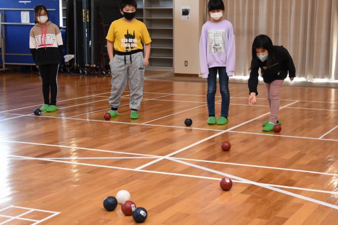 体育館で投げたボッチャのボールを見守る子どもたちの写真