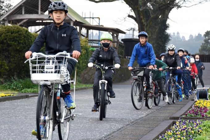 自転車に乗って道路を並んで走る小学生たちの写真