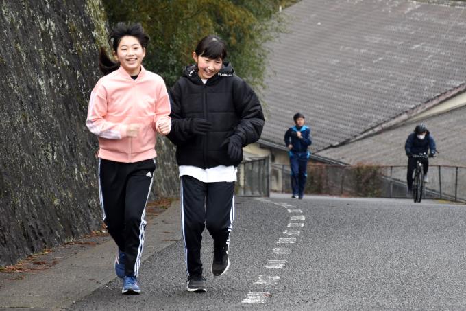 坂道をランニングで登る小学生の写真