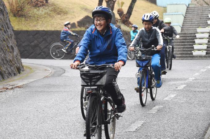 自転車に乗って道路を並んで走る小学生たちの写真