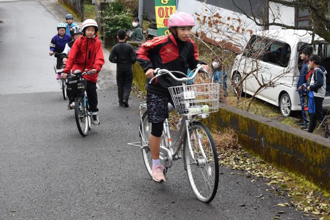 坂道を自転車で登る小学生の写真