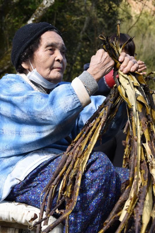 高齢の女性が皮を束ねている写真