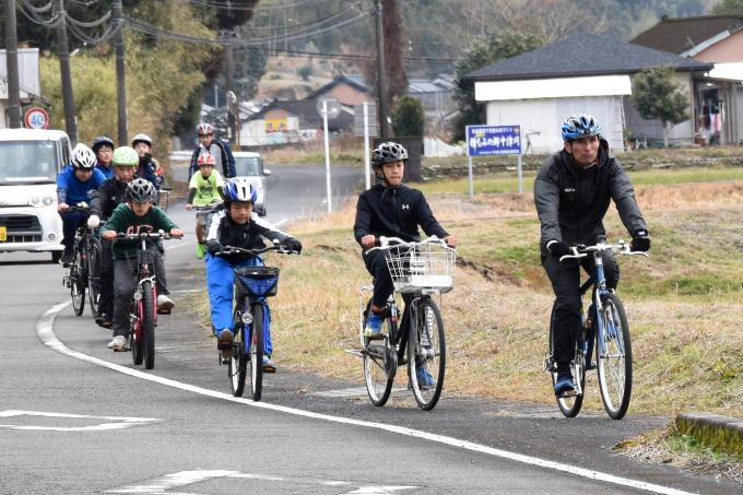 自転車に乗って道路を並んで走る小学生たちの写真