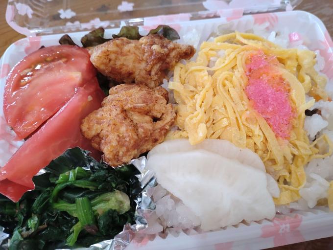 トマト、からあげ、菜っ葉などの入っている配布された弁当の写真