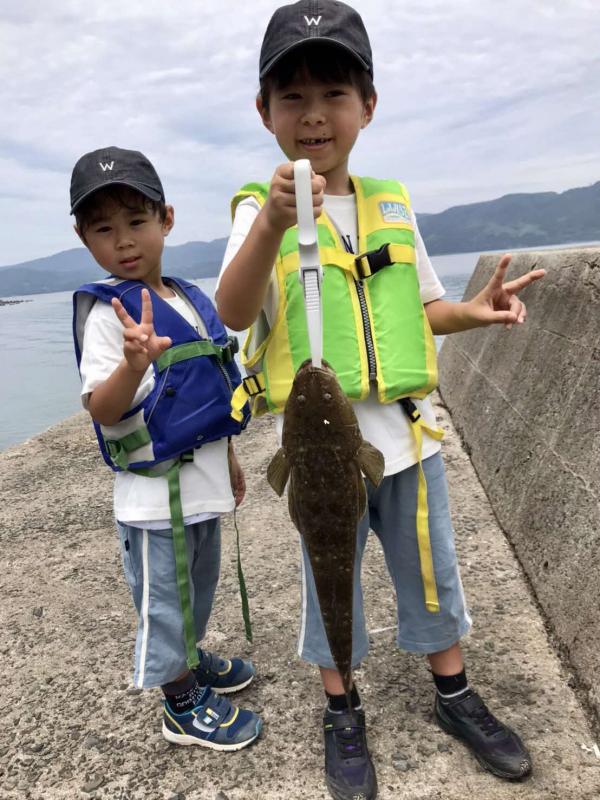 釣ったまごちを見せて記念撮影する男の子の写真