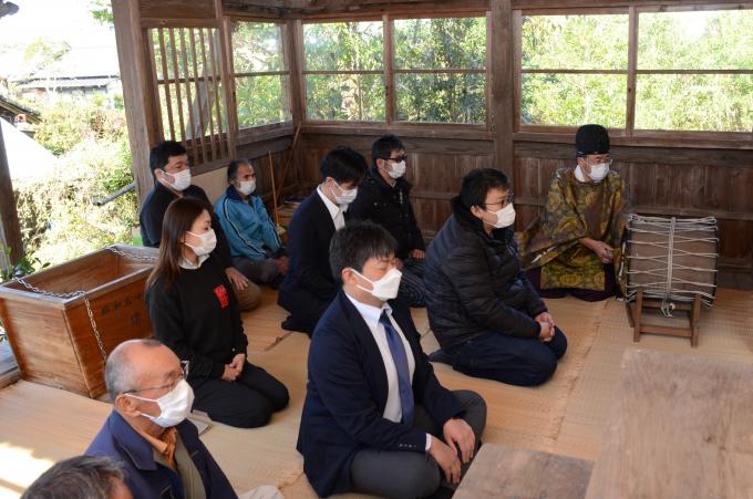 神社で奉納を座って見守る参加者の写真