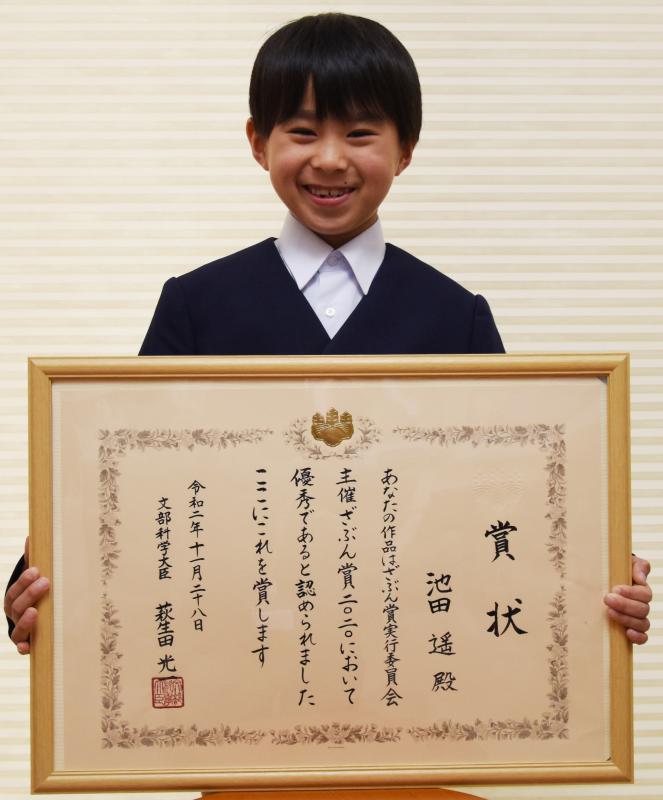 額に入った賞状を見せて記念撮影する池田君の写真