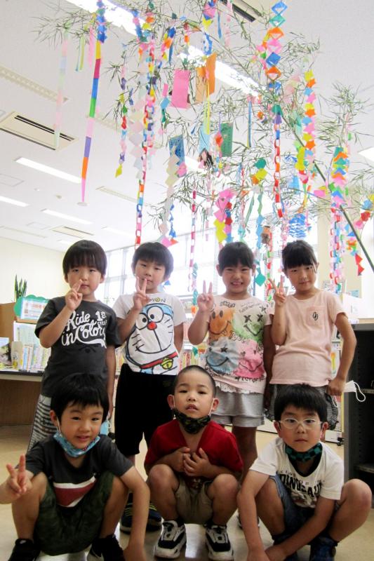 七夕飾りのある室内で飾りと一緒に写る7人の子供たち