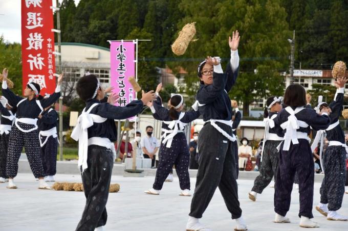 俵を隣の演舞者に投げて渡している写真