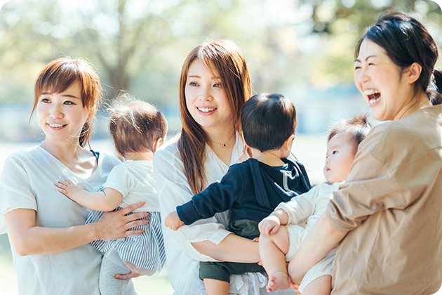 子どもを抱いた母親3人が笑顔で遠くを見ている写真