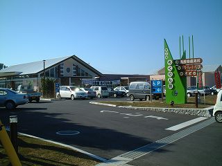 緑色のちくりん館看板の奥に建つちくりん館と駐車場の写真