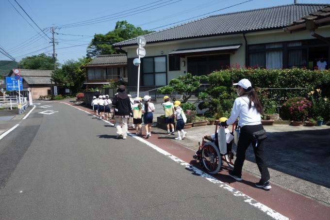 並んで道路の脇を歩く子どもたちと支援員の写真