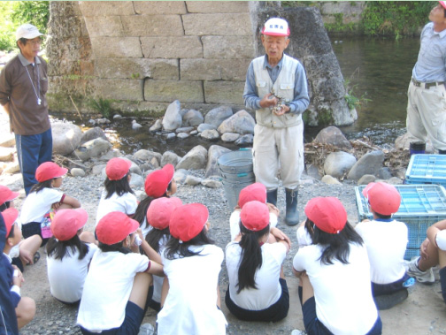 男性の話を座って聞く小学生たちの写真