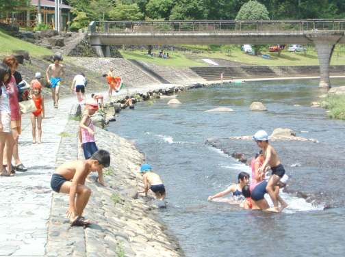 整備された河原に集まって水遊びをする子供たちの写真