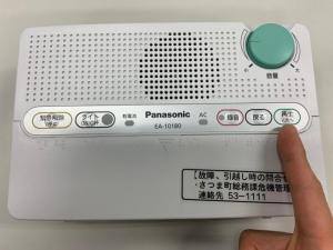 防災行政無線戸別受信機の再生・次へボタンを指さしている画像